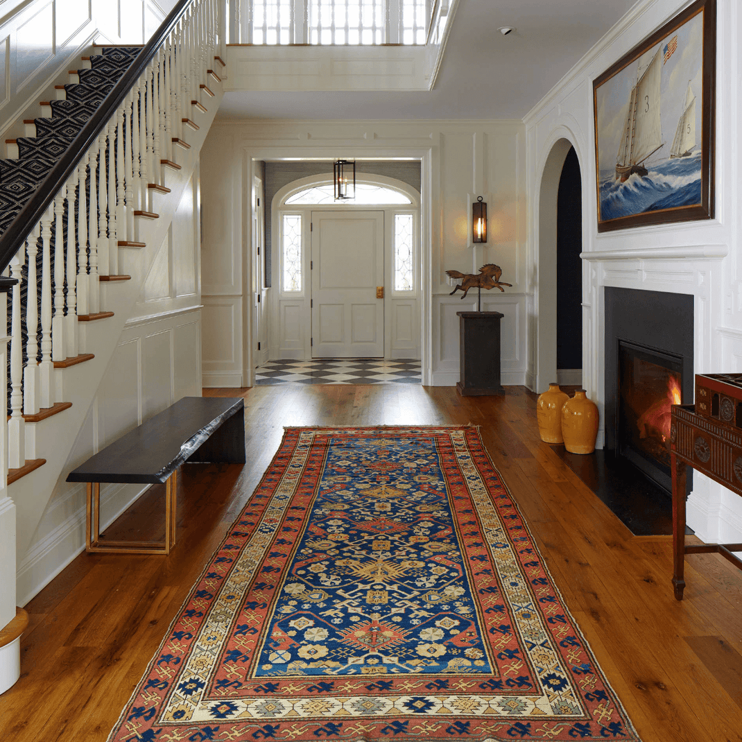 Colorful 12-foot runner rug extending through a traditional entry hall beside a staircase and fireplace