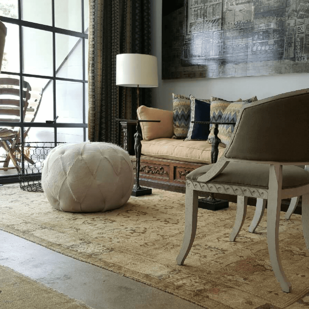 Neutral 5x8 rug beneath a coffee table in a modern living room with large windows
