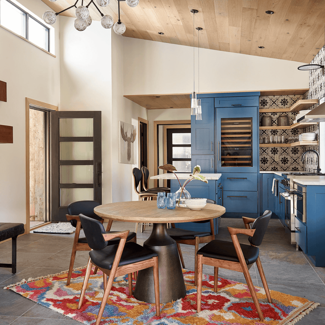 Colorful 7x9 rug beneath a round dining table in a contemporary dining room