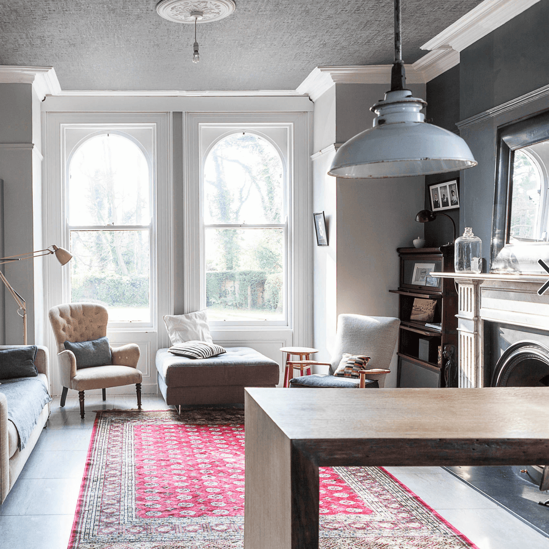 Red 8x10 rug defining the seating area of a bright open-plan living room and kitchen