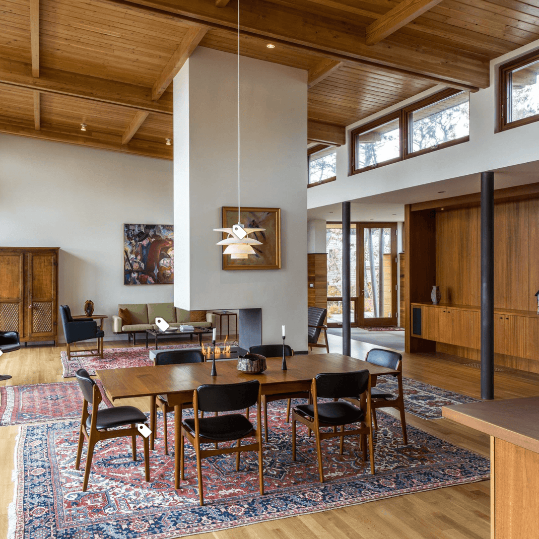 Patterned 8x11 rug beneath a dining table in a spacious open-plan dining room with warm wood finishes
