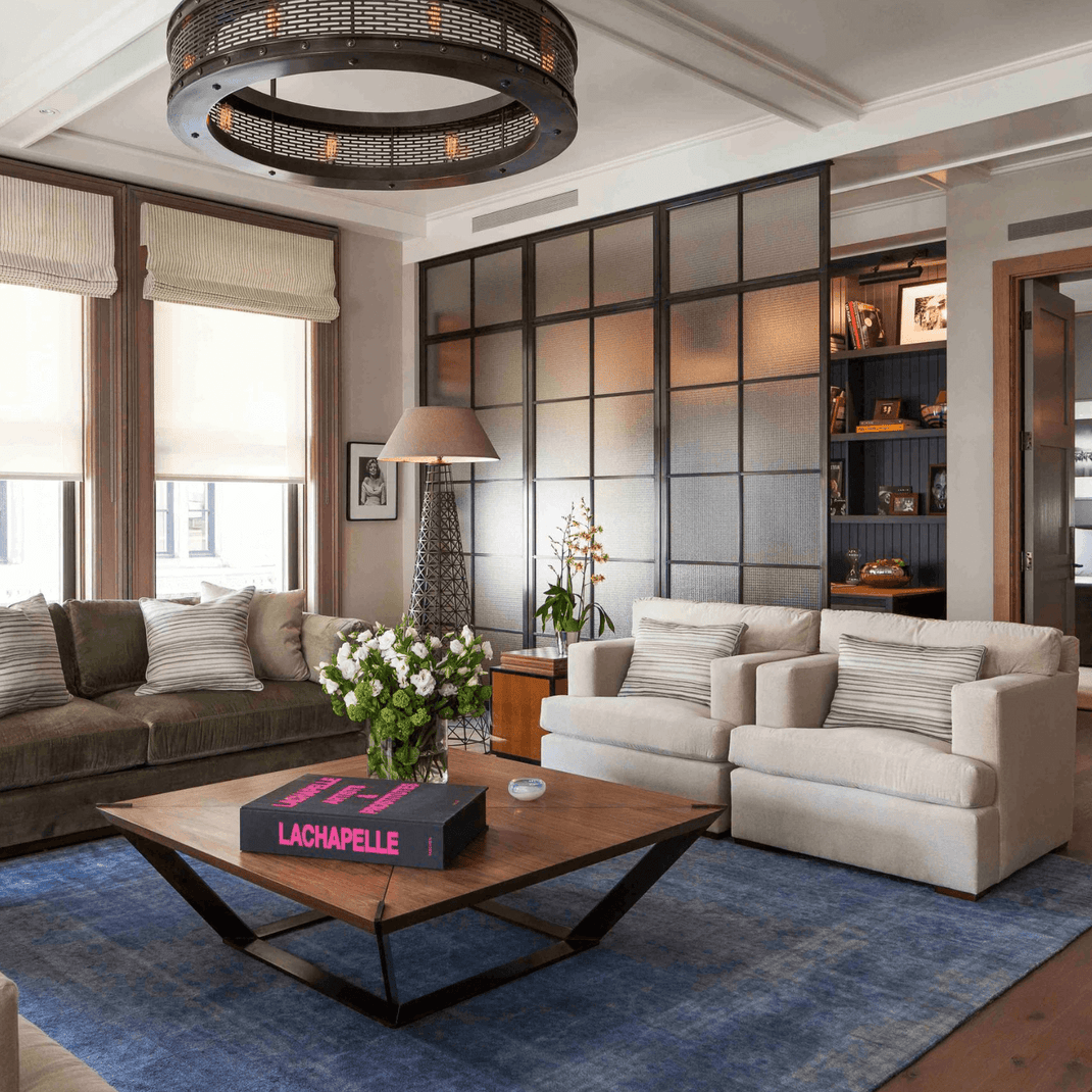 Blue 9x12 rug defining the seating area of a modern living room with neutral armchairs
