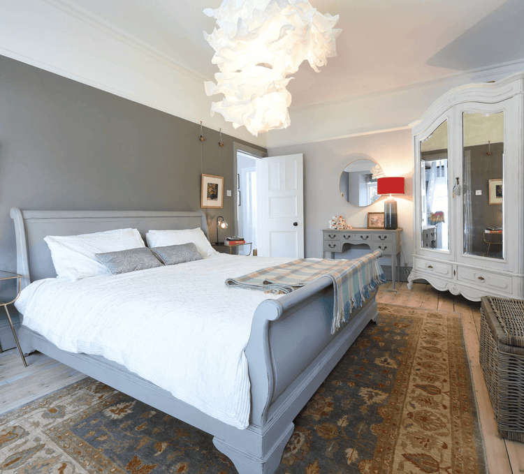 Neutral bedroom rug beside a large bed in a bright master bedroom with classic furniture
