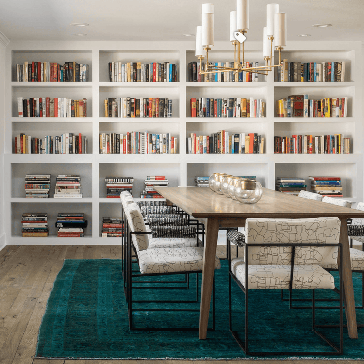 Dining room rug beneath a large table in a bright dining area with built-in bookshelves