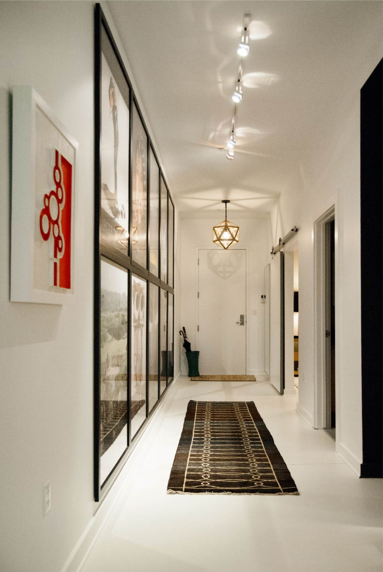 Narrow entryway rug in a bright modern hall with white walls and black-framed glass doors