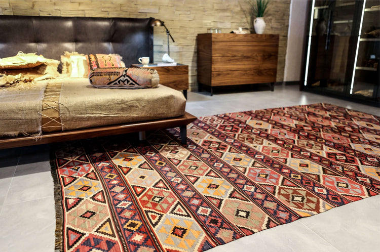 Handmade geometric flatweave rug in a rustic bedroom with wood furniture and an exposed brick wall