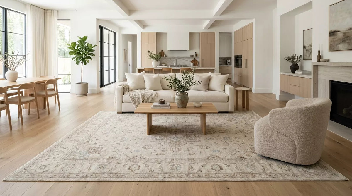 Handmade living room rug in a bright open-plan home with neutral sofa and armchair