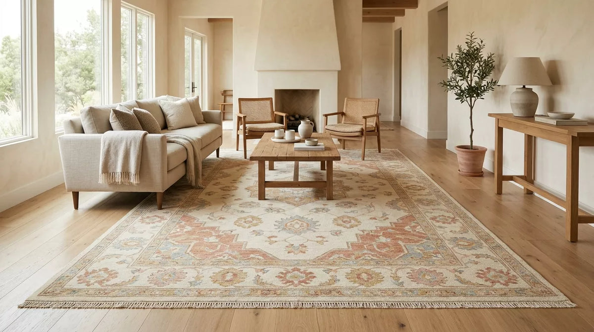 Handmade Oushak area rug by Rug N Carpet anchoring a modern neutral living room. Large vintage-style rug featuring an ivory base with muted terracotta floral motifs