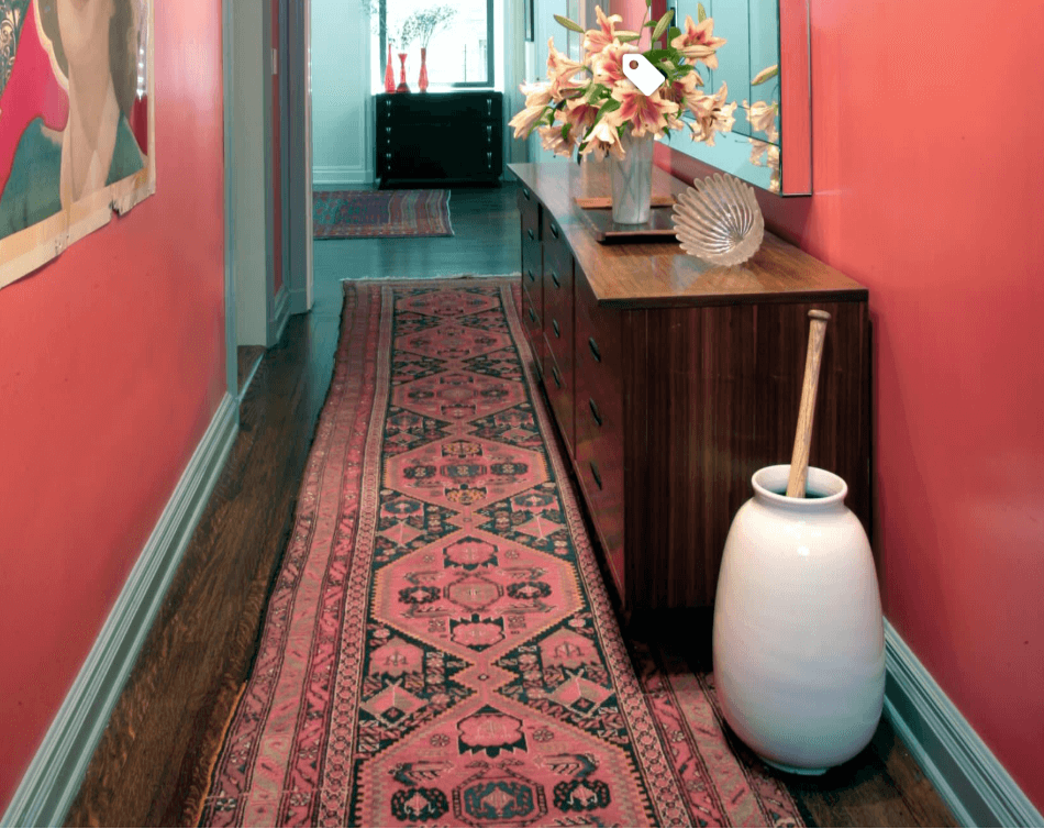 Long patterned runner rug extending through a colorful hallway beside a wooden console table