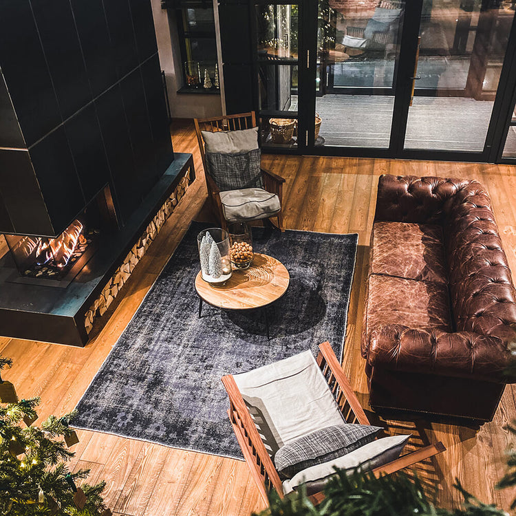 Dark overdyed rug in a modern living room with a leather sofa, fireplace and wood flooring