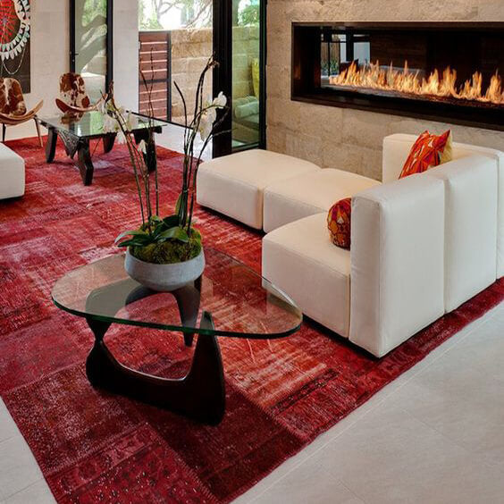 Red patchwork rug beneath modern white seating in a contemporary living room with a fireplace