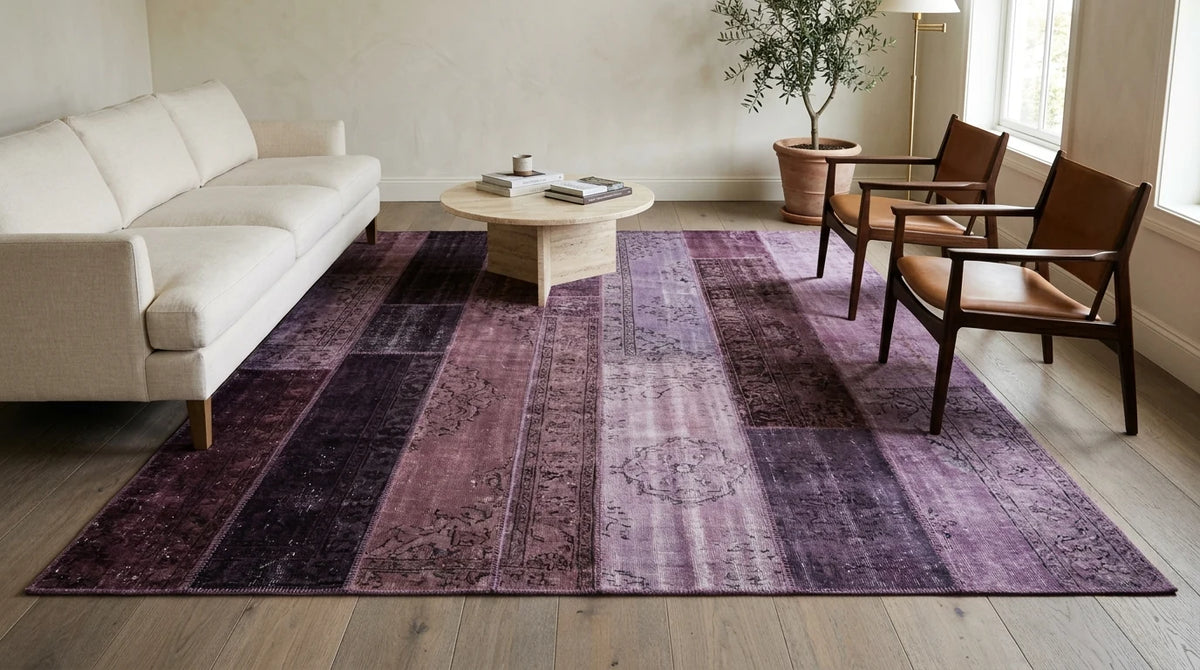 8x10 purple patchwork rug in dark plum, eggplant and lilac strips with a cream linen sofa and leather armchairs in a bright living room