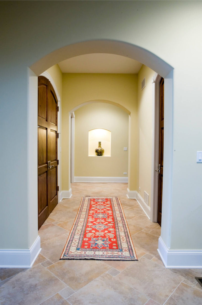 Red vintage runner rug placed in a long arched hallway