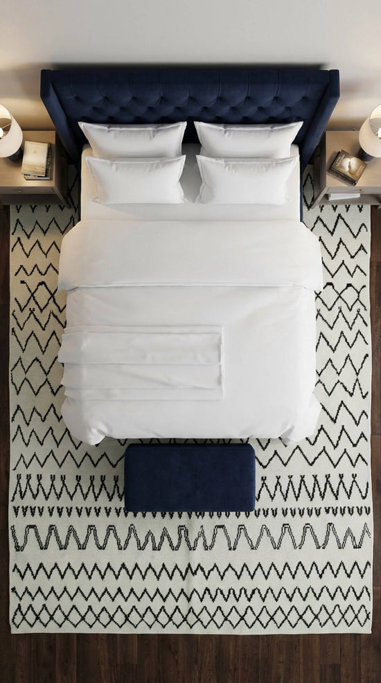 Black and white Moroccan rug with geometric patterns styled in a modern bedroom beneath a bed, adding texture and contrast.